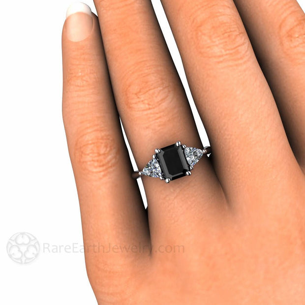 Natural Black Diamond Engagement Ring on the Finger, three stone style with diamond trillions from Rare Earth Jewelry