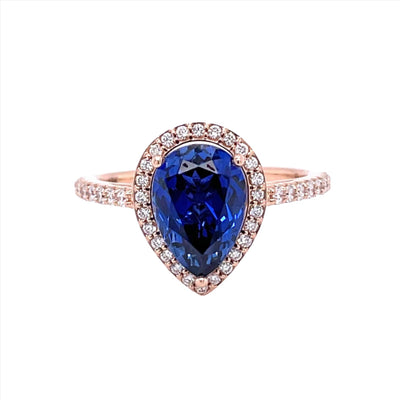 A Blue Sapphire pear engagement ring with diamond halo, teardrop shaped engagement ring in rose gold from Rare Earth Jewelry.