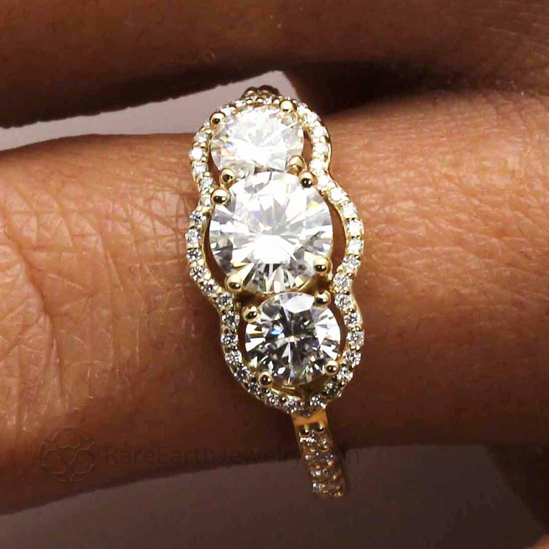 Close up of Vintage Inspired Moissanite Engagement Ring  on the Finger, Three Stone Diamond Halo | Rare Earth Jewelry